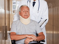 A man sitting on a wheelchair while wearing a neck brace